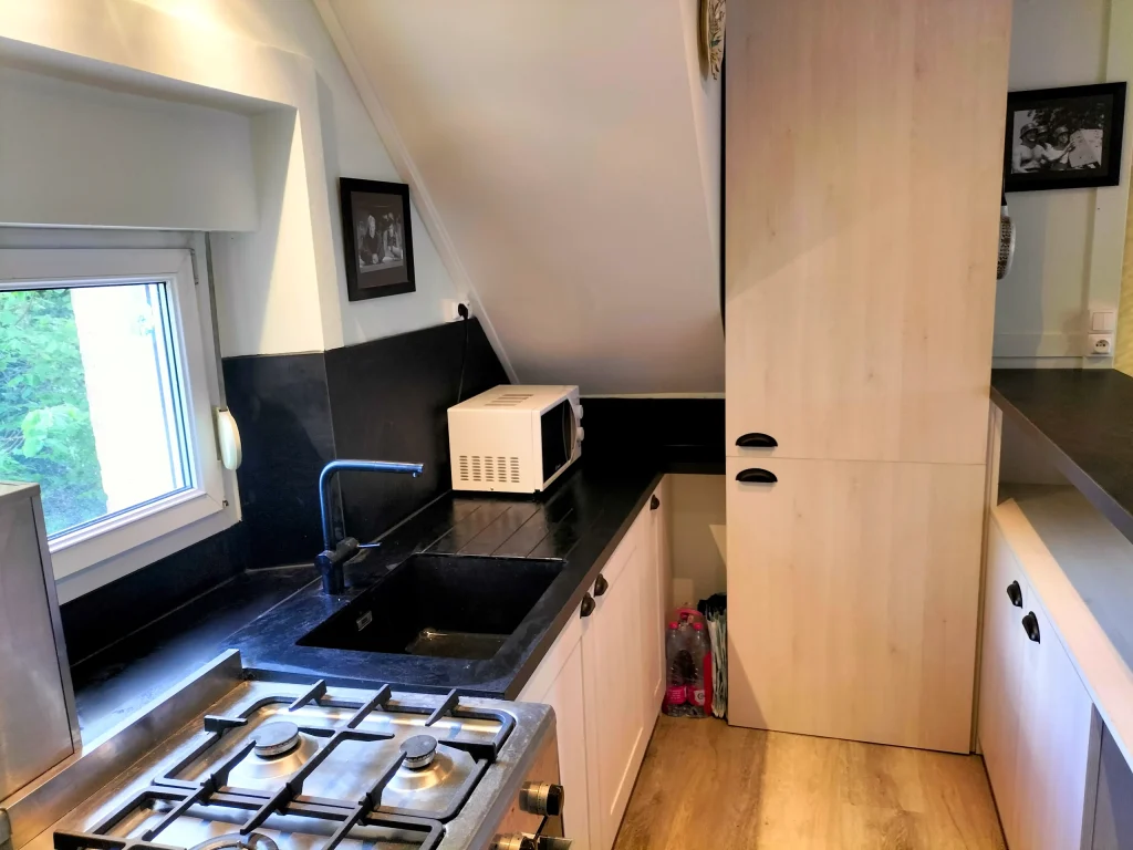 Détail de la cuisine rénovée sous escalier en bois noir à Mayenne