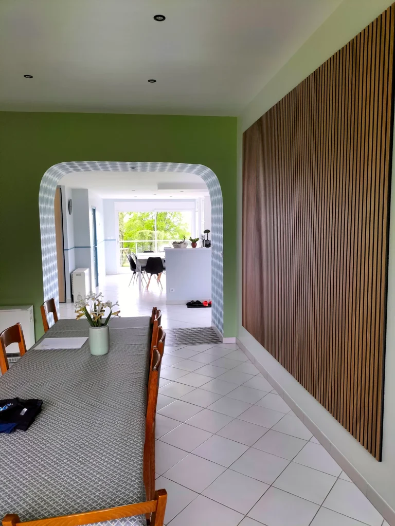 Vue depuis la salle à manger sur l’arche décorée et le panneau de lattes bois