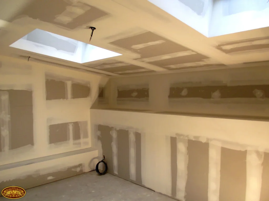 Pose de plaques de plâtre avec traitement des joints, doublage des murs et plafond avec rampants et puits de lumière.