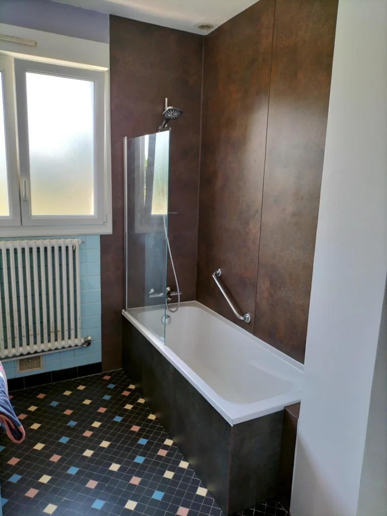 Espace bain rénové avec revêtement mural effet métal et paroi vitrée