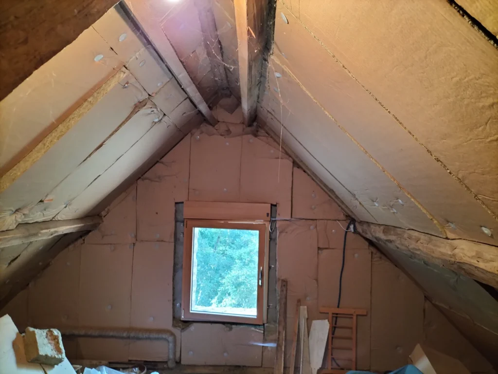 Grenier à l’état brut dans les Alpes Mancelles, isolant incomplet et défauts visibles avant rénovation.