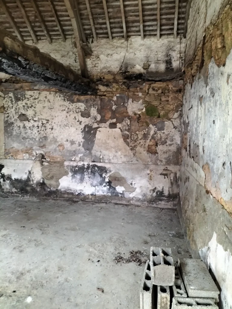 Mur intérieur fortement cloqué et détérioré dans un bâtiment ancien